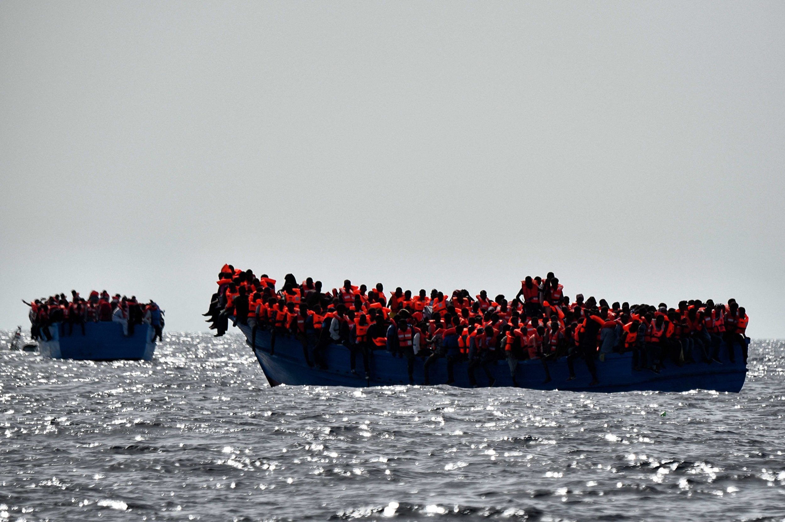 TOPSHOT - Migrants wait to be rescued as they drift in the Mediterranean Sea some 20 nautical miles north off the coast of Libya on October 3, 2016. Italy coordinated the rescue of more than 5,600 migrants off Libya, three years to the day after 366 people died in a sinking that first alerted the world to the Mediterranean migrant crisis. (Photo by ARIS MESSINIS / AFP) (Photo by ARIS MESSINIS/AFP via Getty Images)