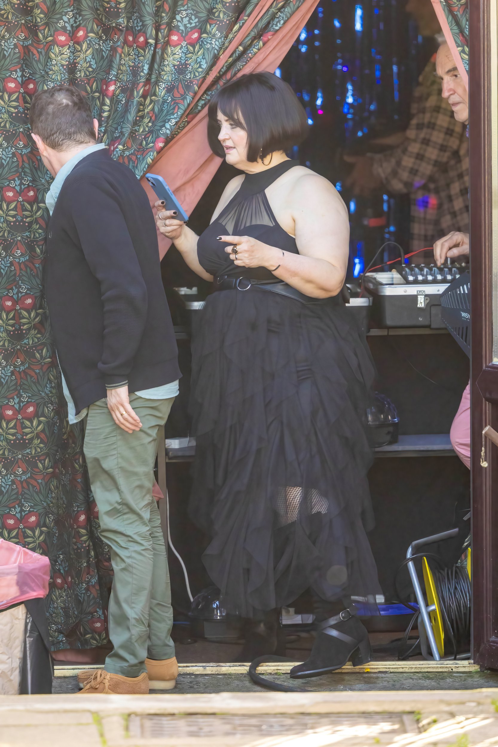 Ruth Jones as Nessa leaving a building with a DJ set on Gavin and Stacey set