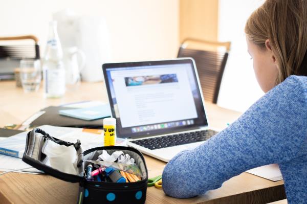 Young girl doing schoolwork on a laptop while sitting at a table
