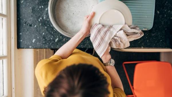 A woman dries dishes in the office kitchen.