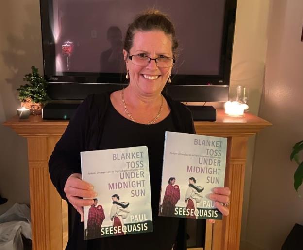 Woman holding up two books.