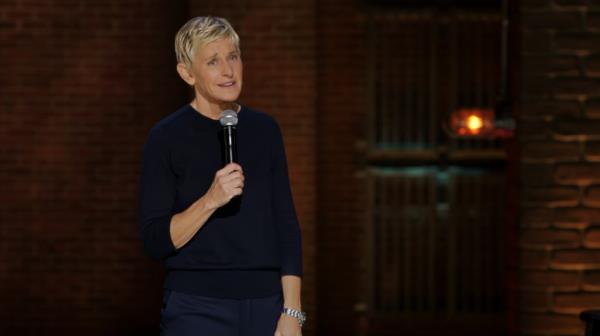 Ellen DeGeneres holding a microphone, speaking about her decision to ditch cosmetic procedures for a Netflix show