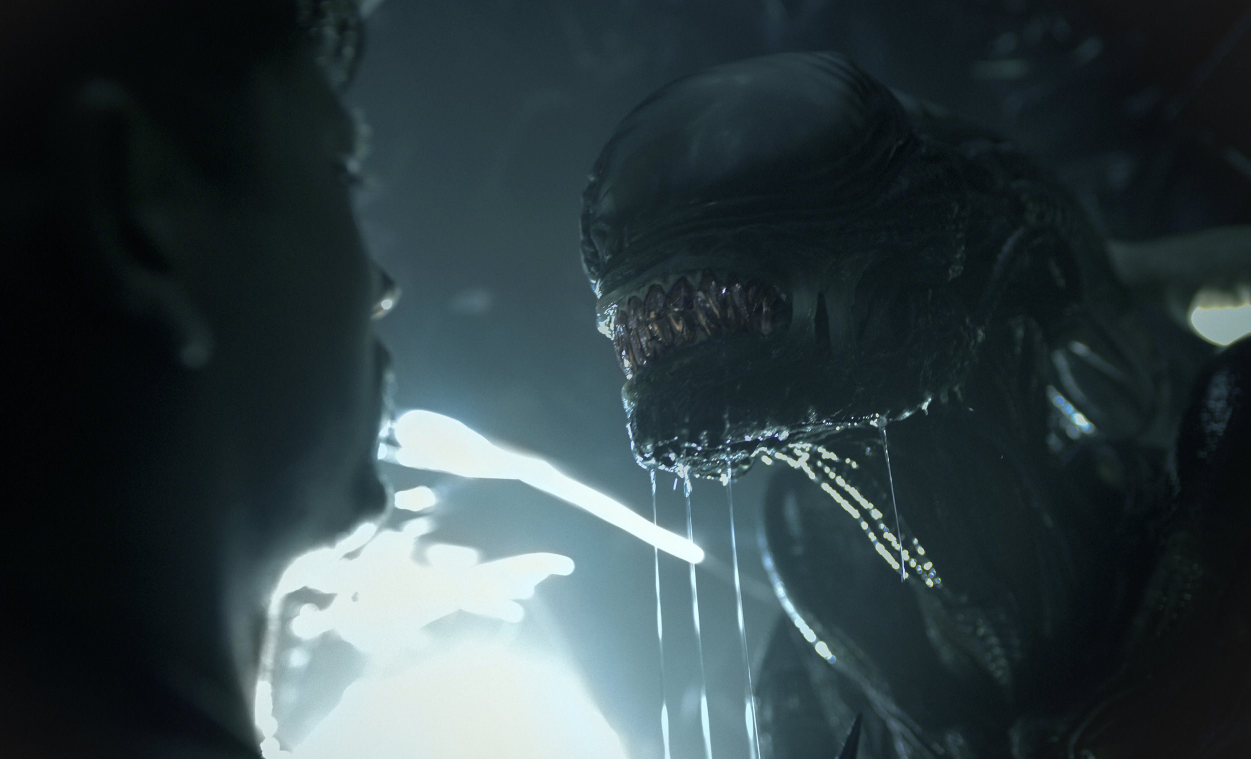 A Xenomorph dripping with drool appraoches a human male in a scene from Alien: Romulus