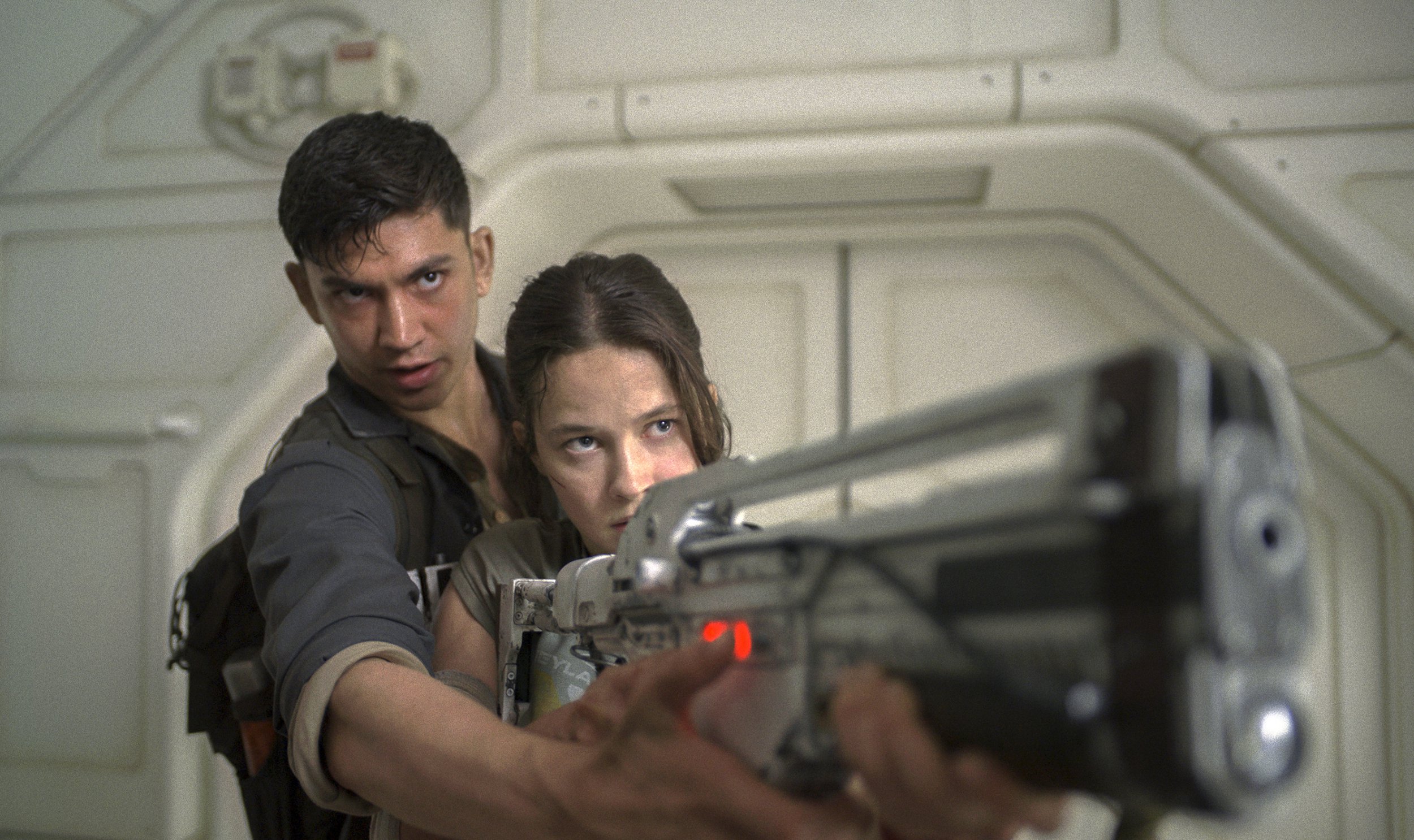 Archie Renaux as Tyler shows Cailee Spaeny as Rain how to hold a gun in a scene from Alien: Romulus