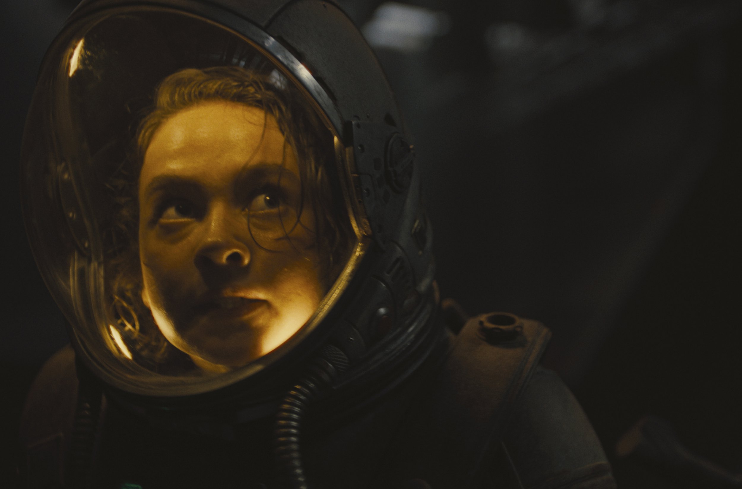 Cailee Spaeny looks upwards and scared in an astronaut's suit in a scene from Alien: Romulus