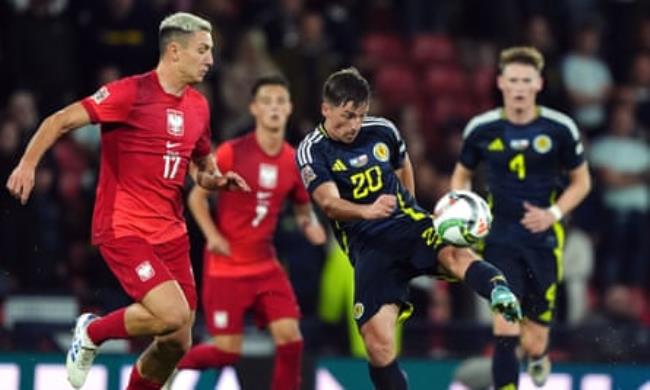 Ryan Gauld in blue strikes the ball while being marked by Poland’s Bartosz Slisz