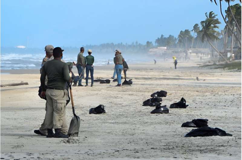 Members of the National Parks Institute (INPARQUES) collect oil residue at the Boca de Yaracuy beach in Falcon State, after an apparent spill from the El Palito refinery