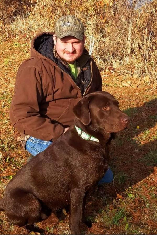 Undated photo of Boone McCrary from Greeneville, Tenn., sitting with a dog, who died while attempting a rescue during Hurricane Helen