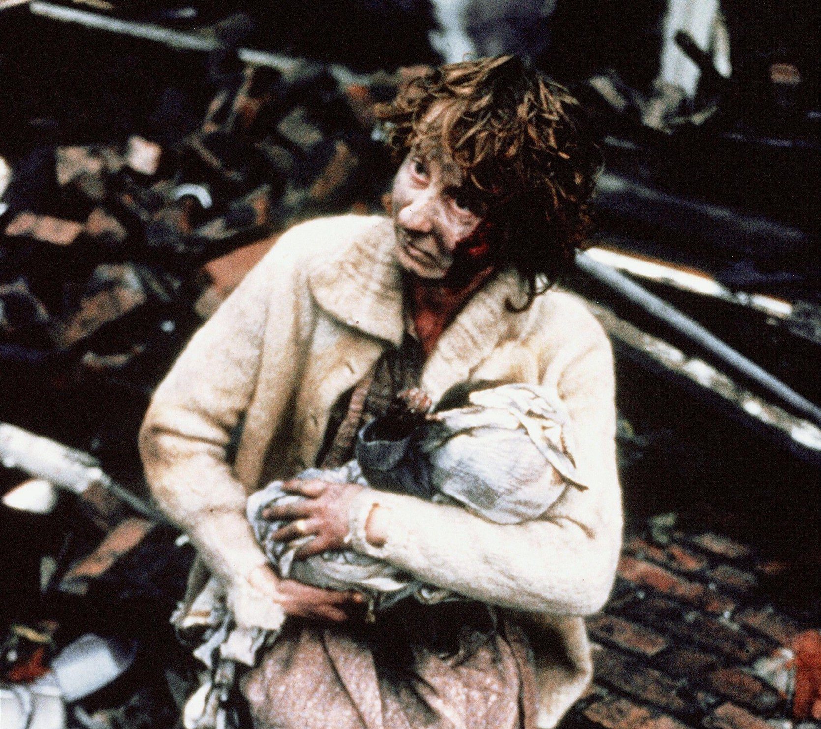 A scene from the film Threads - a woman is holding her baby and has blood on her