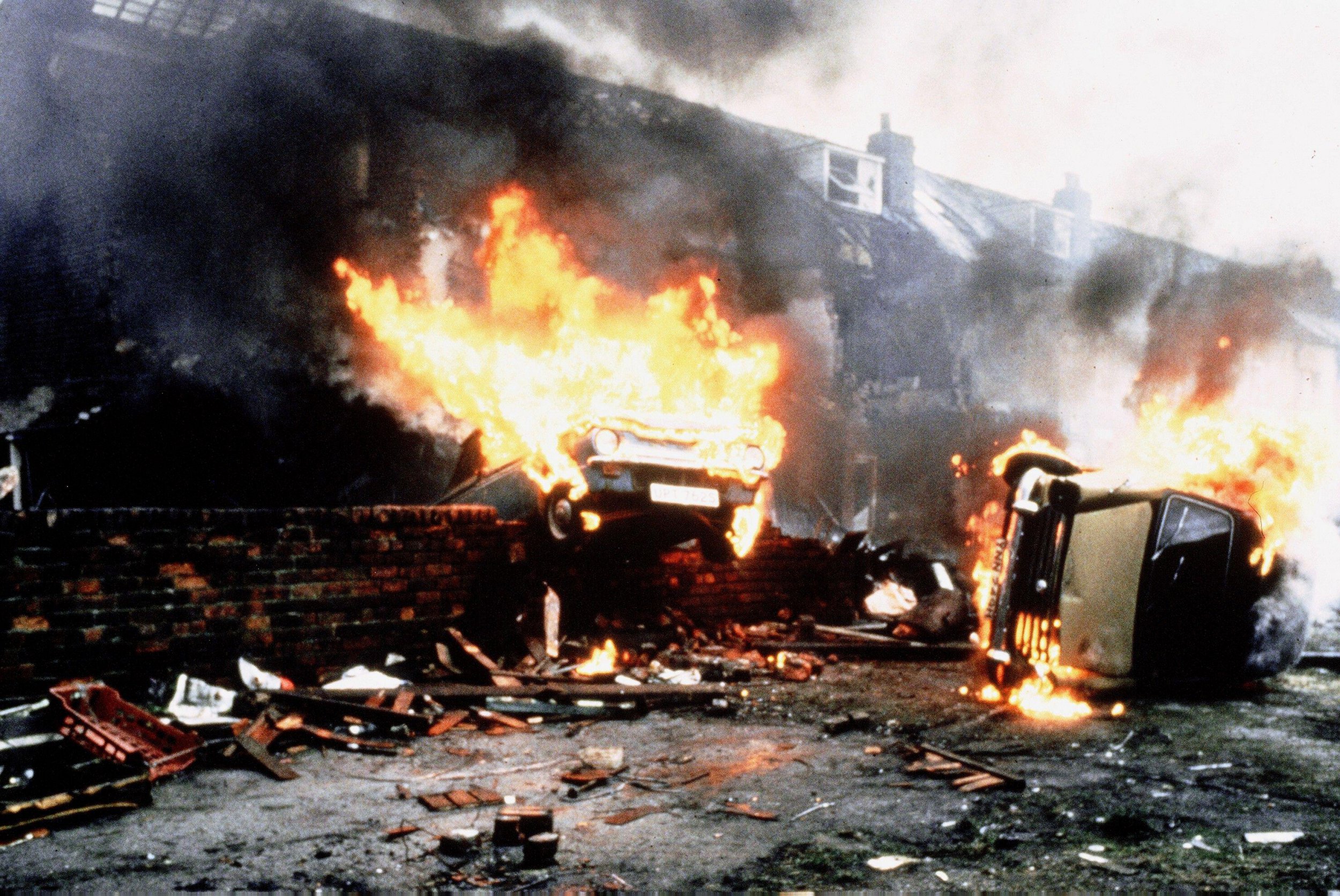 A scene from Threads - cars are in flames on a street littered with debris
