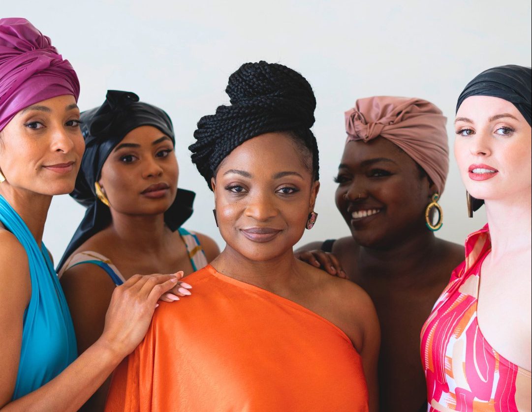 Danielle wears orange and stands in the centre surrounded by models