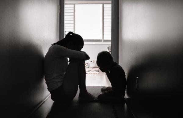 Sad little boy with his mommy sitting on the floor at home.