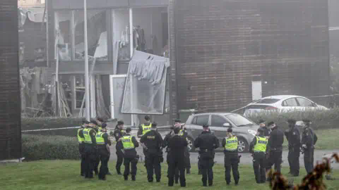 ANDERS WIKLUND/TT NEWS AGENCY/AFP Policemen stand in front of a damaged building after a powerful explosion occurred in the early morning of September 28, 2023 in a housing area in Storvreta outside Uppsala, Sweden.