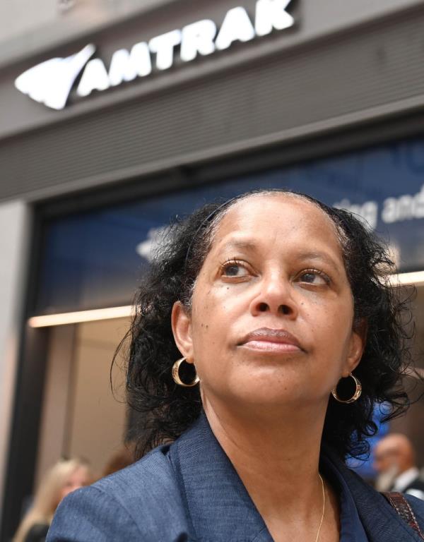 A photo of Ophelia Rawles in front of Amtrak in Moynihan Train Hall at Penn Station.