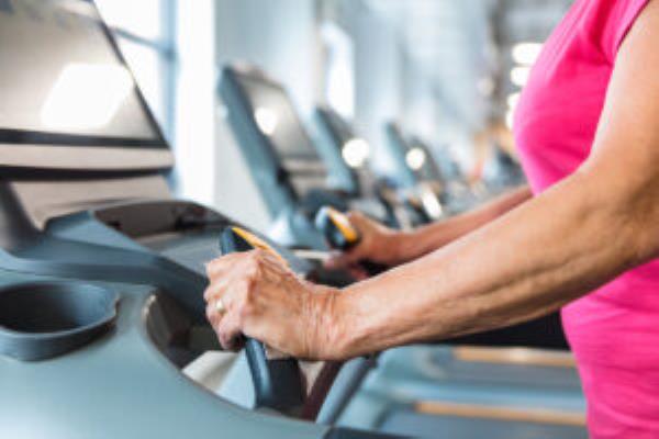 Close up of senior woman hands on the treadmill at gym. Elderly woman exercising on treadmill machine.