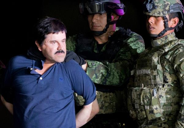A handcuffed Joaquin "El Chapo" Guzman is made to face the press as he is escorted to a helicopter by Mexican soldiers and marines at a federal hangar in Mexico City, Jan. 8, 2016