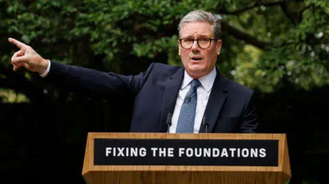 Getty Images Keir Starmer at lectern with the words Fixing The Foundations