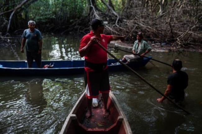 Four men and two boats in shallow water