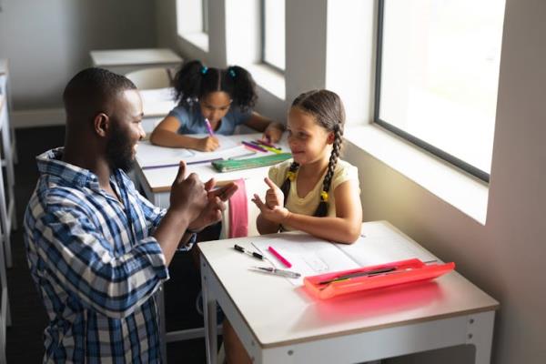 A teacher communicating with a primary school student in sign language