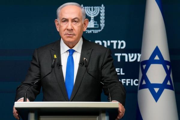 Benjamin Netanyahu at a lectern. He looks stern. An Israeli flag is behind him