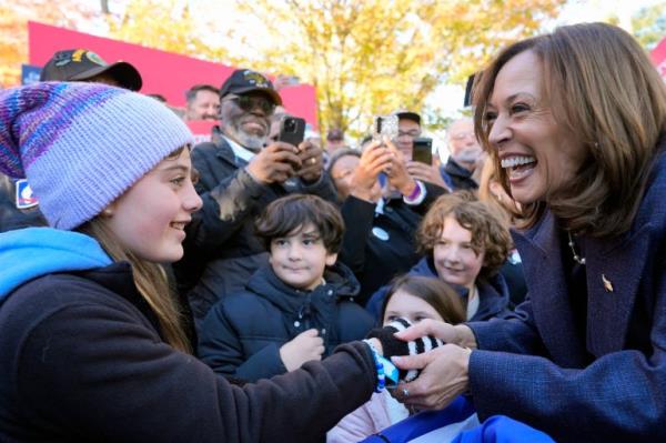 Kamala Harris greets supporters, shaking the hand of a young girl.