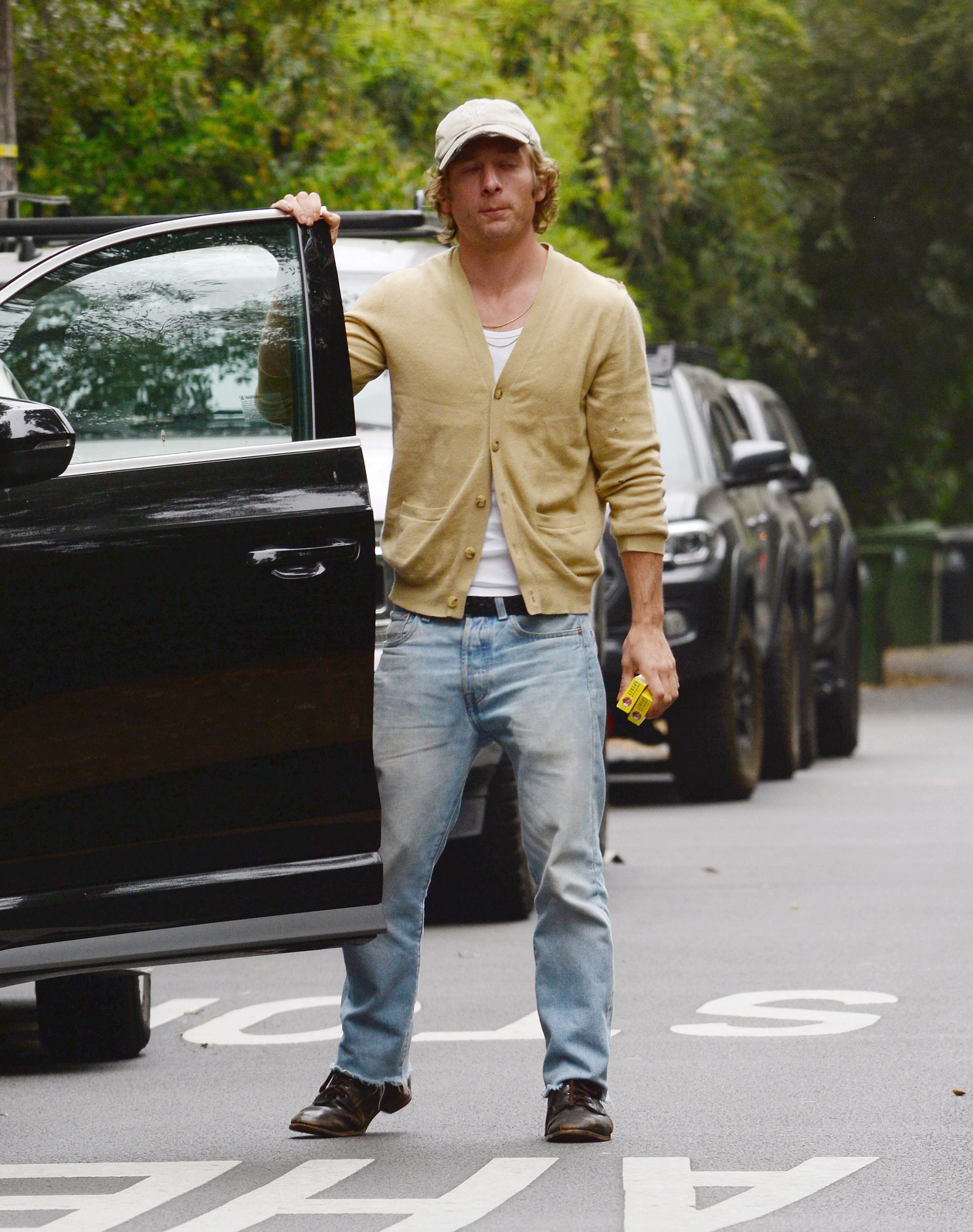 Jeremy Allen White holds a car door on the street