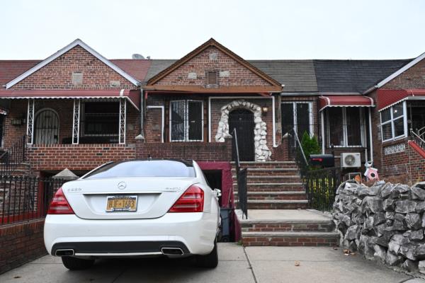 Federal investigators removing boxes of evidence from a brick house at 613 Troy Avenue in Flatbush Brooklyn, with a white car parked in front