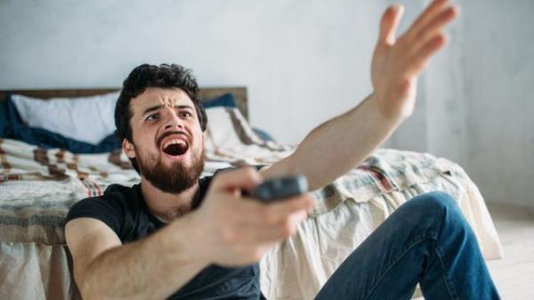 Man is angry while he is watching television on the floor