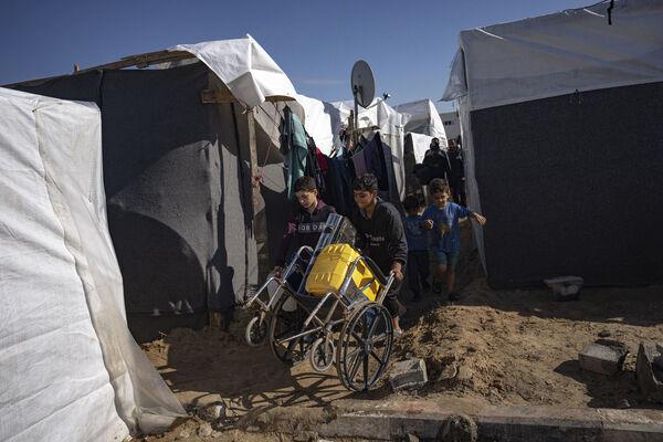 Palestinians displaced by the Israeli bombardment of the Gaza Strip carry supplies in a UNDP-provided tent camp in Khan Younis, Wednesday, Nov.15, 2023. (AP Photo/Fatima Shbair) Palestinians displaced by the Israeli bombardment of the Gaza Strip carry supplies in a UNDP-provided tent camp in Khan Younis, Wednesday, Nov.15, 2023. (AP Photo/Fatima Shbair)