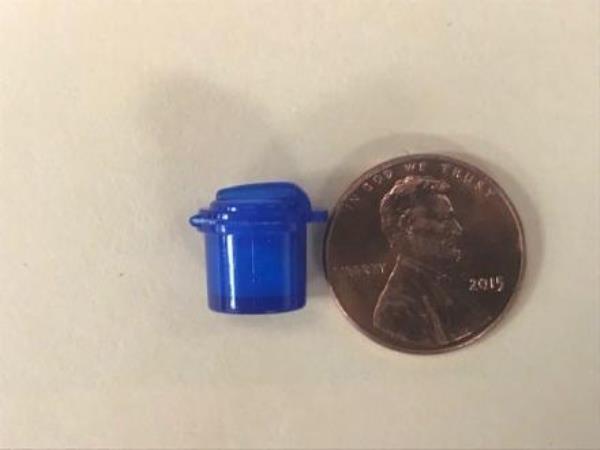 Trash can drug vial next to a penny for scale.