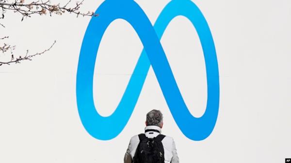FILE - A person stands in front of a meta sign outside of the company's headquarters in Menlo Park, Calif., March 7, 2023. 
