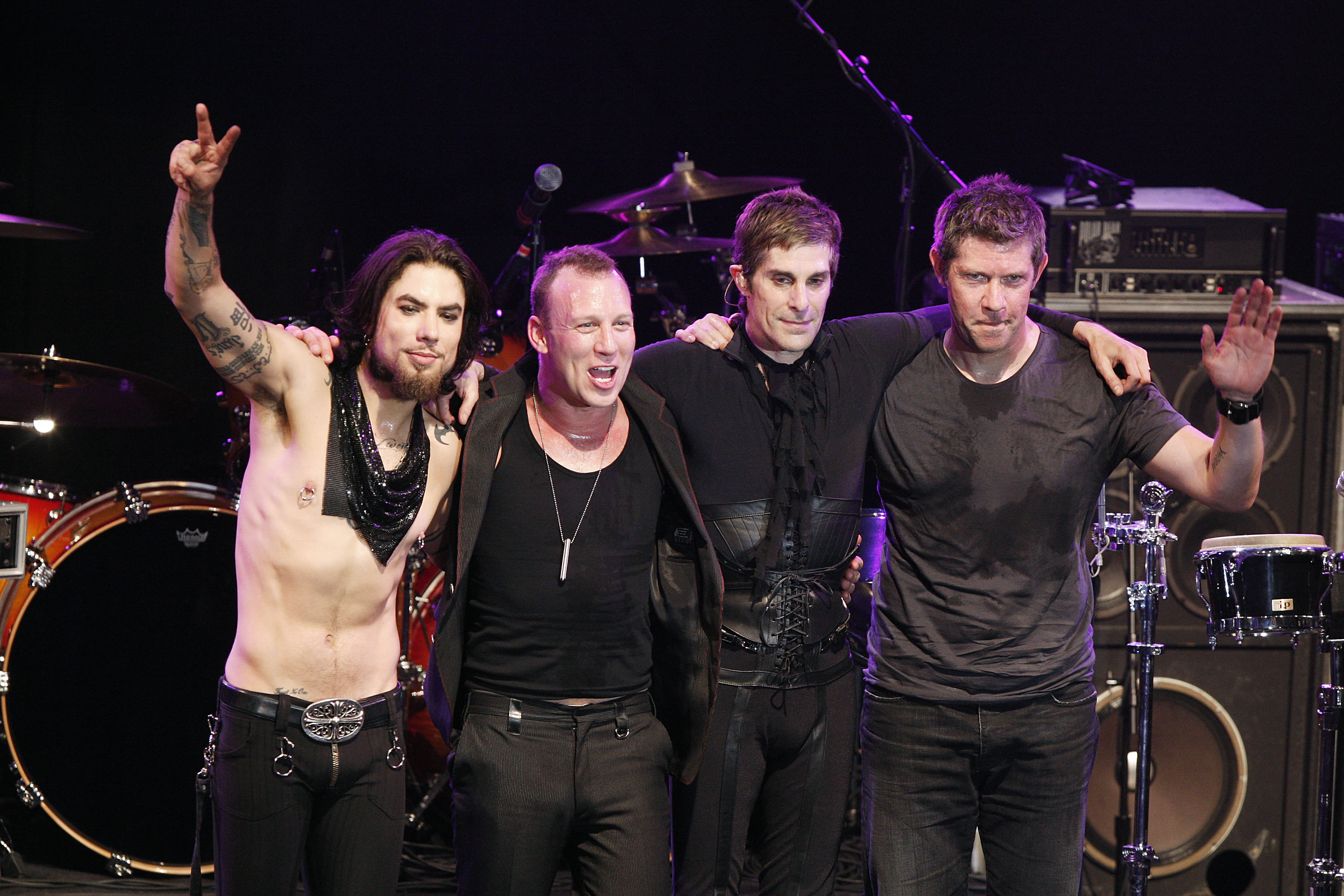 Dave Navarro, Stephen Perkins, Perry Ferrell and Eric Avery of Jane's Addiction standing onstage with their arms around each other