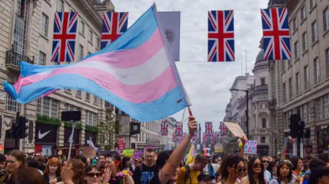 Getty Images A person waves a transgender rights flag during a demonstration 