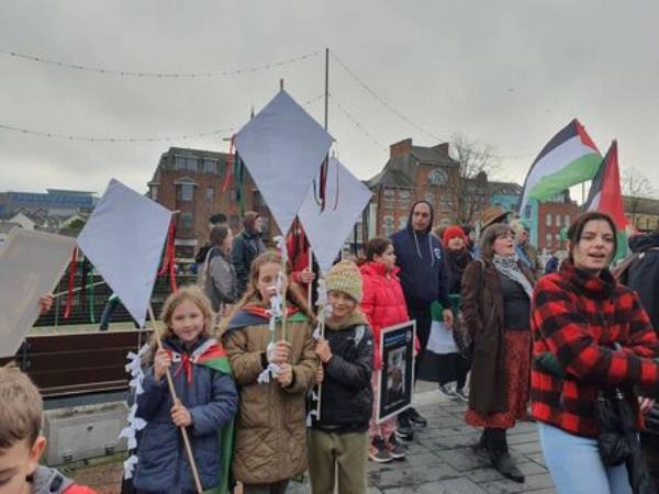 Three girls hold kites at a rally for Palestine in Cork.
