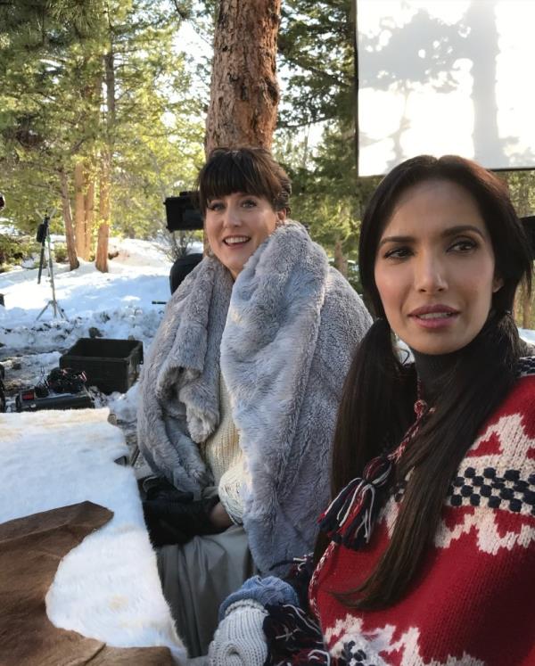 Naomi Pomeroy smiling sitting next to Padma Lakshmi. 