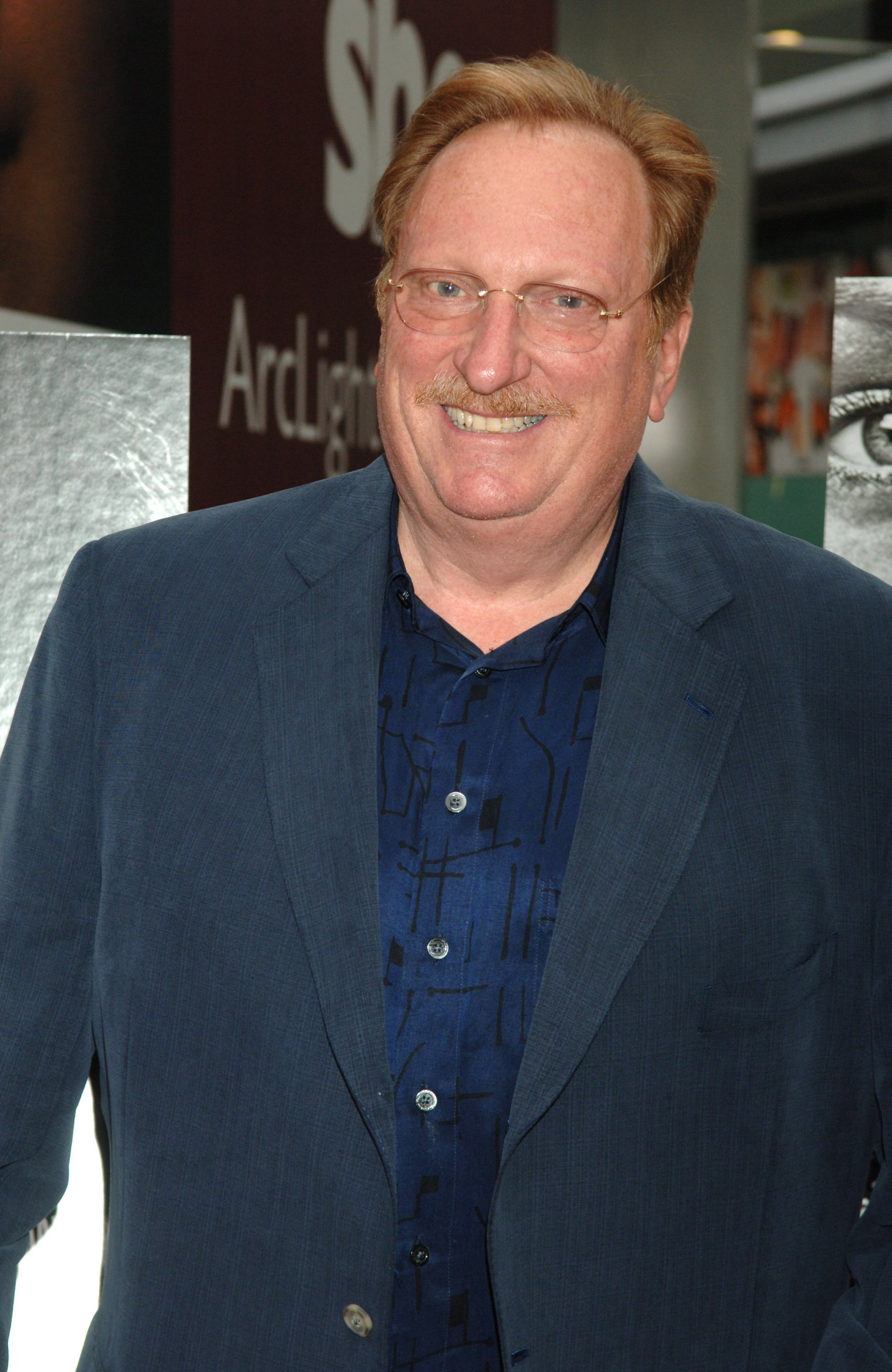 Jeffrey Jones smiles on the red carpet in a blue suit and navy shirt during the Deadwood Season Premiere