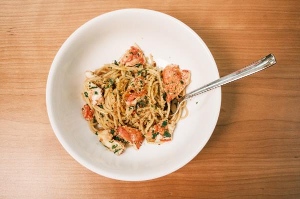 Bowl of pasta, lobster and tomatoes, sitting on a table top