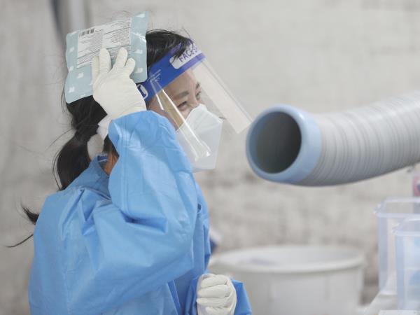 A medical staff member stands in front of an air conditioner, holding an ice pack, to beat the heat at a public health center at Daegu, July 6. (Yonhap)