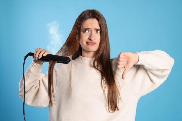 A woman used a flatiron and does a thumbs down.
