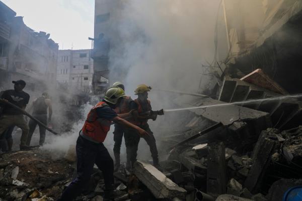 Palestinian civil defence personnel work at the site of an Israeli rocket attack in Al-Shati refugee camp in the west of Gaza City.
