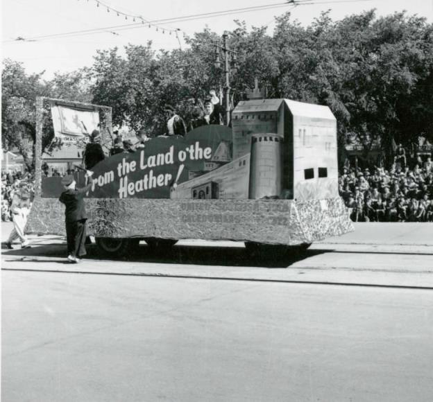 A black and white photo of a parade float with the image of a castle