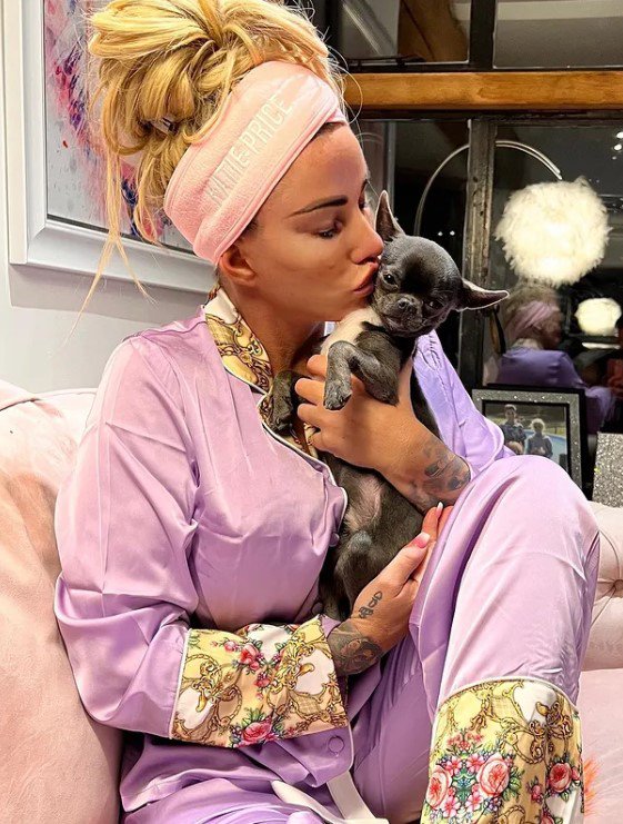 Katie Price wearing a head band and kissing a small dog
