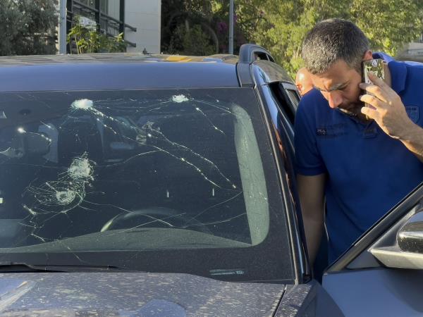 Police officer looks at a car damaged by exploding pager