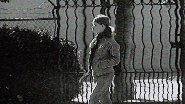 A woman walking down a street captured on a grainy video camera in The Poughkeepsie Tapes