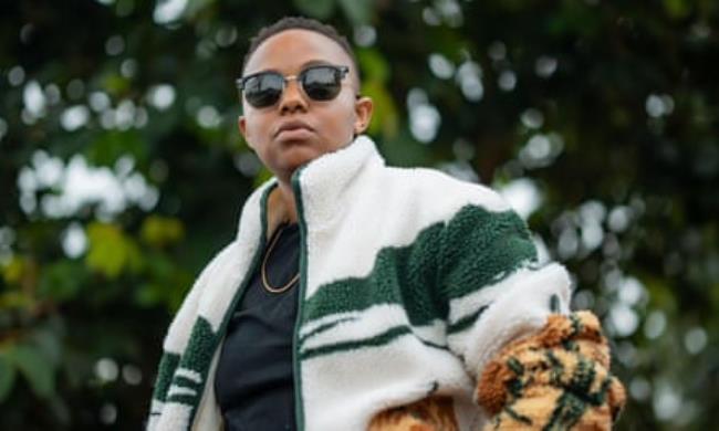 Muriithi wears sunglasses and a striped fleece and looks directly a the camera.