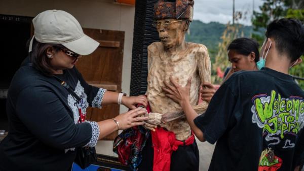 Family members of the Toraja ethnic group dress the exhumed body of their relative. — AFP pic