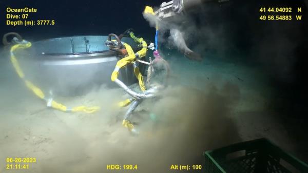 The remote vehicle's camera showed a close-up view of two robot arms maneuvering the retrieval equipment as a shark swam up to inspect.