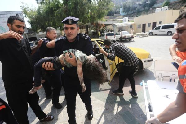 A Hamas officer carries a girl wounded following retaliatory strikes against the militant group on Sunday.