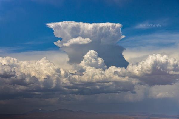 Giant cumulonimbus cloud rising over lower clouds.