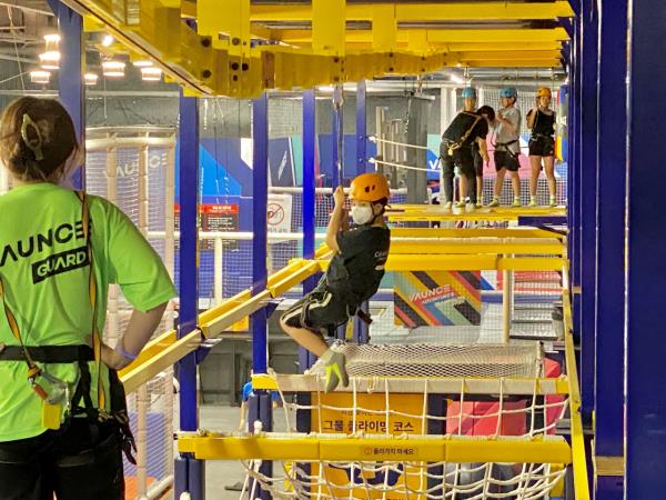 A safety assistant watches a boy approach on a zip line. (Hwang Joo-young/The Korea Herald)